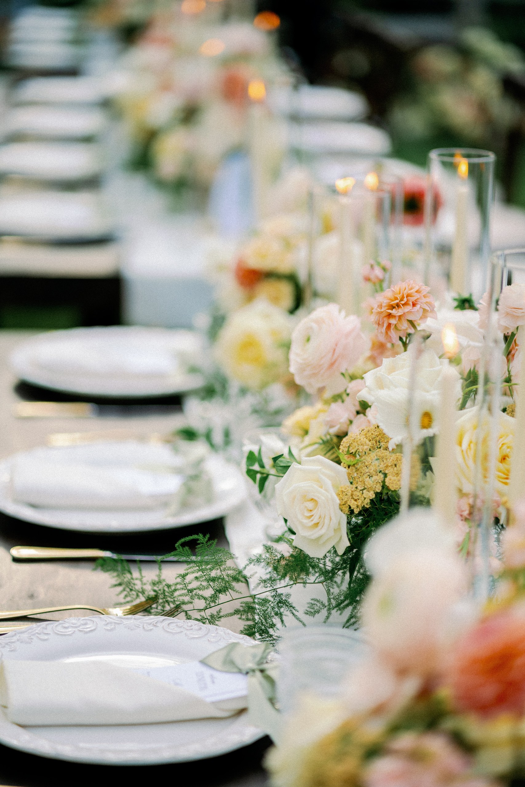Long reception table with garden florals and candlelight at an Olivenhain backyard wedding